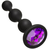 The Booty Bling Purple Silicone Anal Beads by Doc Johnson feature a sleek, triple-bead design in black silicone, along with a flared base that showcases a large, faceted purple gem—perfect for those who love a touch of bling.